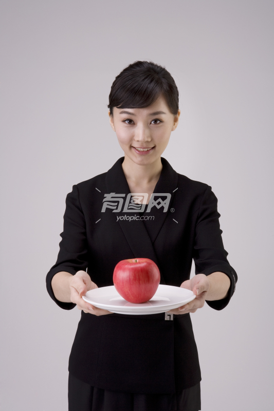 穿职业套装端着苹果的女性