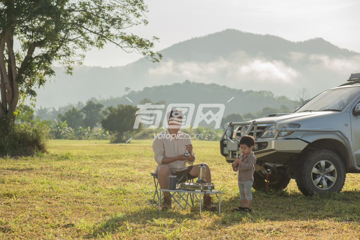 日落时分，一家人在露营车旁野餐父子在山上玩耍