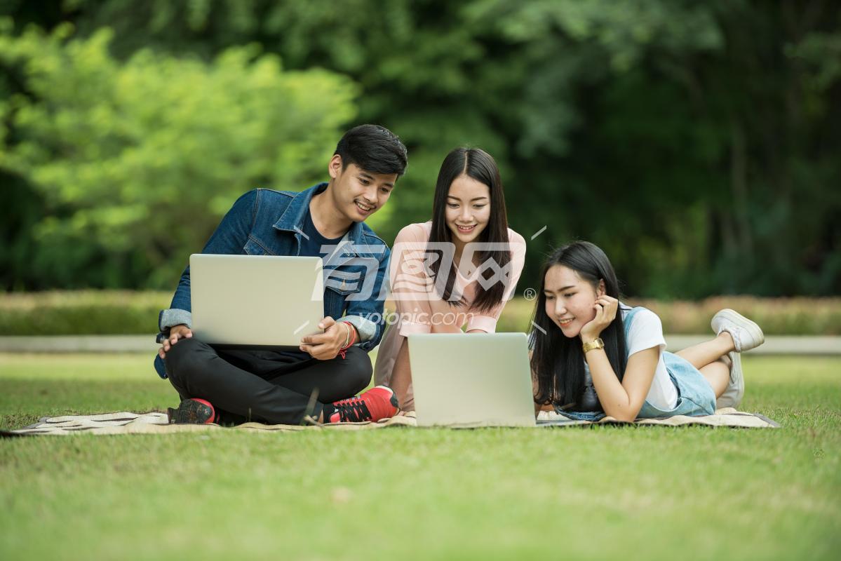 学生在草坪上使用笔记本电脑
