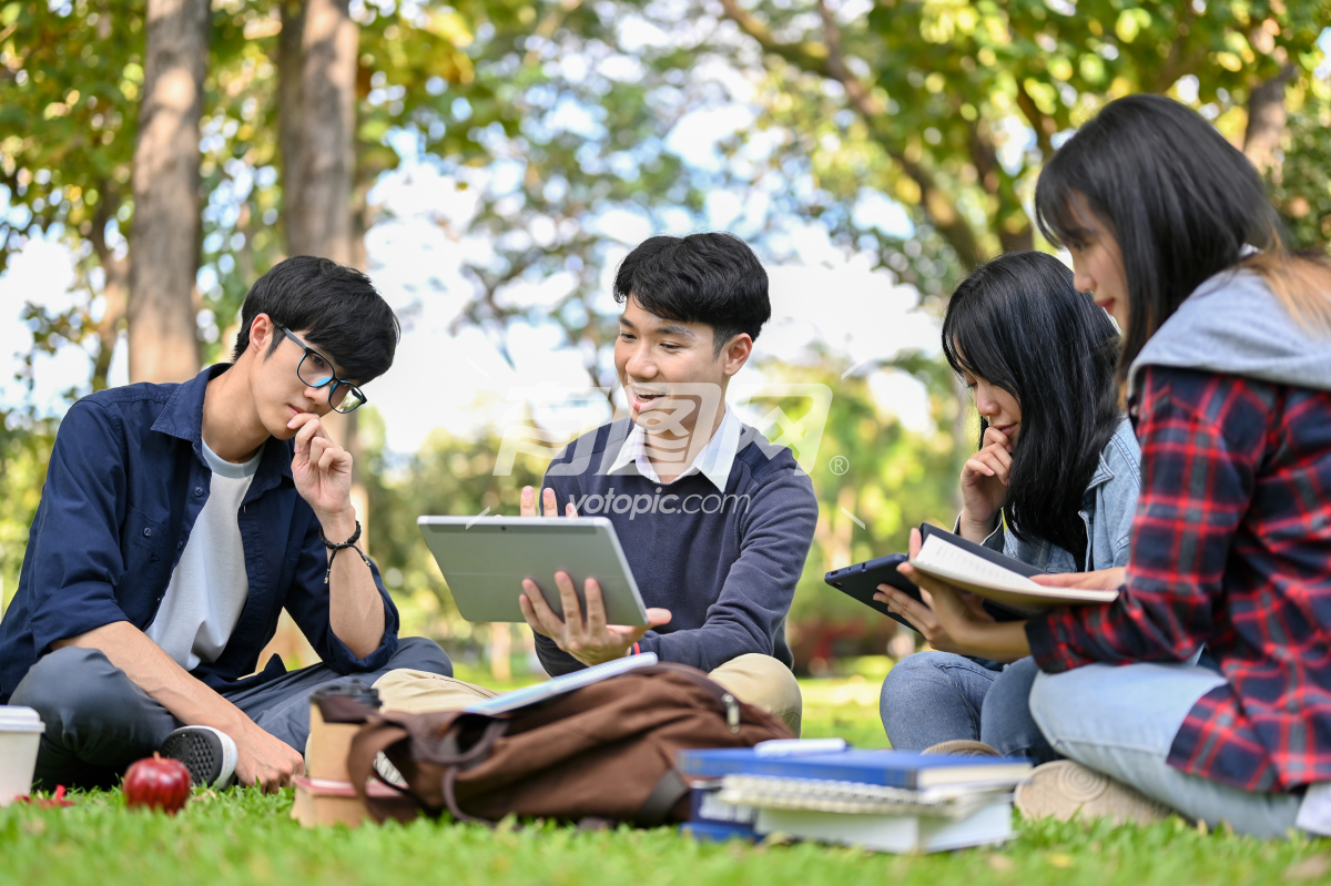 亚洲大学生坐在草坪上讨论