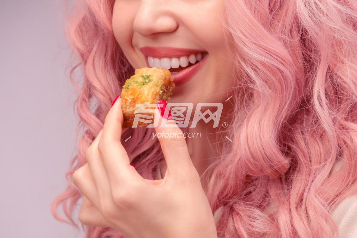 粉红色卷发的女人正在吃点心特写