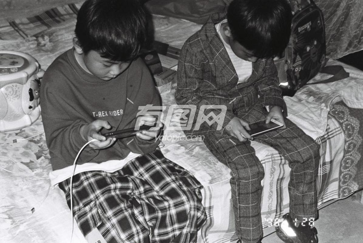 床边两个儿童玩手机